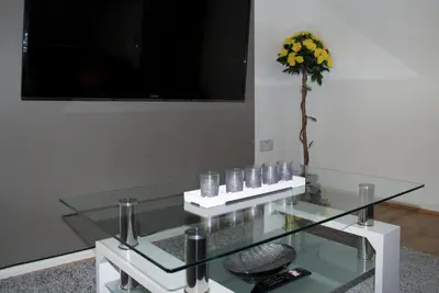 a glass coffee table with a vase of flowers on it at Stylish and Comfortable Home Away From Home in Liverpool