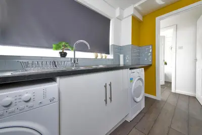a kitchen with a sink and a washing machine at Stylish and Comfortable Home Away From Home in Liverpool