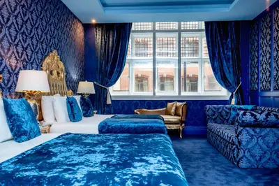 a blue room with two beds and a couch at The Dixie Dean Hotel in Liverpool