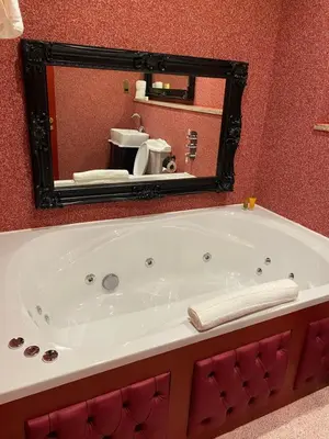 a bath tub in a bathroom with a mirror at The Dixie Dean Hotel in Liverpool
