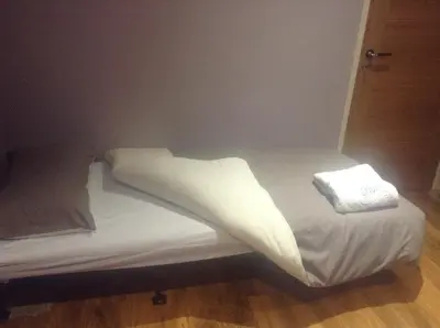 a bed with white sheets and pillows on it at The Anfield Apartment in Liverpool