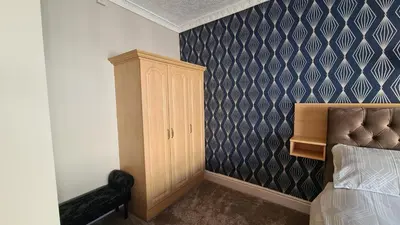 a bedroom with a bed and a wooden cabinet at The Kimberley B&B in Blackpool