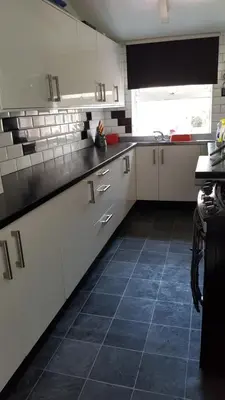 a kitchen with white cabinets and a blue tile floor at The Kimberley B&B in Blackpool