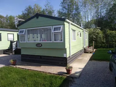 a green and black tiny house in a yard at Borwick Lakes Haven in Burton