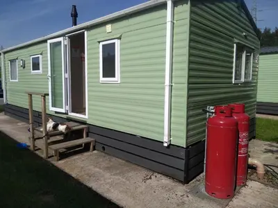 a green tiny house with a fire hydrant next to it at Borwick Lakes Haven in Burton
