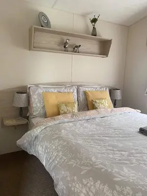 a bedroom with a bed with a white comforter at Borwick Lakes Haven in Burton