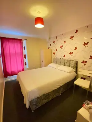 a bedroom with a large bed with a pink window at Chilton Hotel in Blackpool