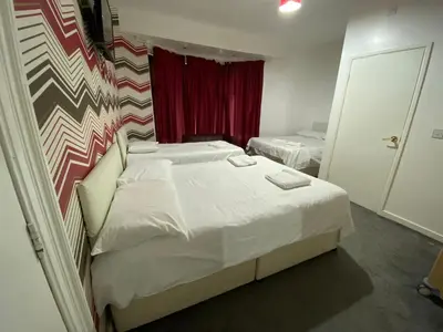a small bedroom with two beds and a red curtain at Chilton Hotel in Blackpool