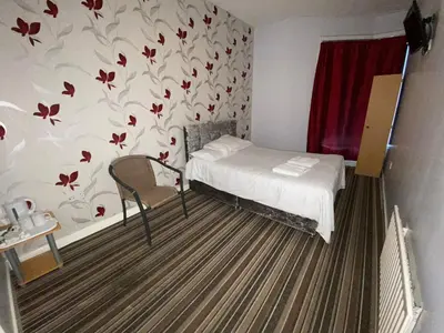 a small bedroom with a bed and a chair at Chilton Hotel in Blackpool