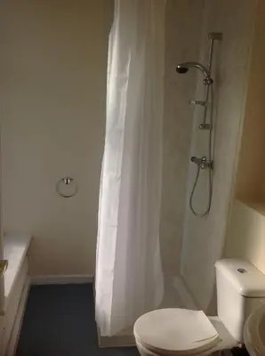 a bathroom with a toilet and a shower with a shower curtain at Chilton Hotel in Blackpool