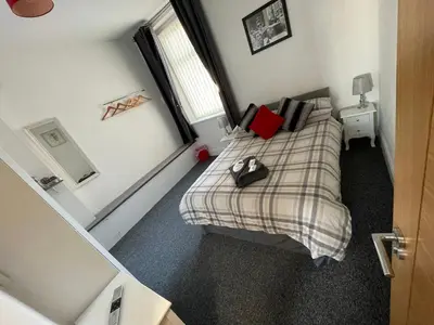 a small bedroom with a bed with a plaid blanket at Harleys Reads Avenue in Blackpool