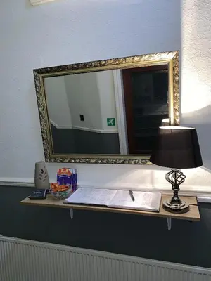a mirror on a shelf with a lamp and a book at Harleys Reads Avenue in Blackpool