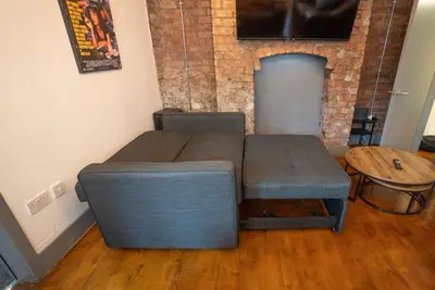 a bedroom with two beds and a table and a brick wall at Urban Apartment Free Parking Near Pleasure Beach in Blackpool