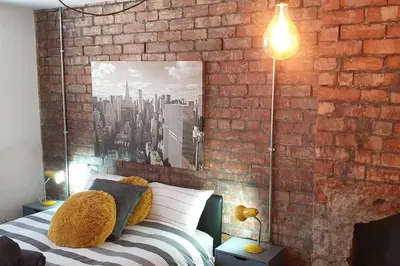 a bedroom with a brick wall and a bed with pillows at Urban Apartment Free Parking Near Pleasure Beach in Blackpool