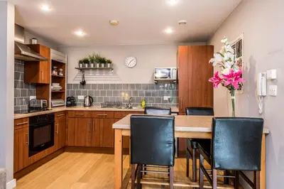 a kitchen with a wooden table and black chairs at Host & Stay - York Place Apt in Liverpool