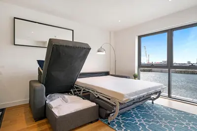 a bed and a chair in a room with a window at Host & Stay - Waterfront View in Liverpool
