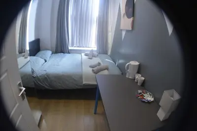 a small bedroom with a bed and a table at Kensington Guest House Liverpool in Liverpool