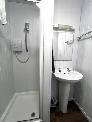 a white bathroom with a sink and a shower at Central Cove Guesthouse in Blackpool