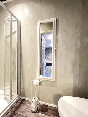 a bathroom with a mirror and a tub and a sink at Central Cove Guesthouse in Blackpool