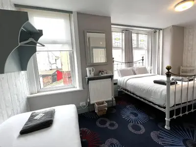 a bedroom with two beds and two windows at Central Cove Guesthouse in Blackpool