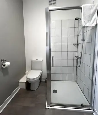 a bathroom with a shower and a toilet at Central Cove Guesthouse in Blackpool