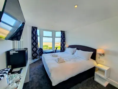 a bedroom with a large bed and a television at The Kerswell Hotel Sea Front in Morecambe