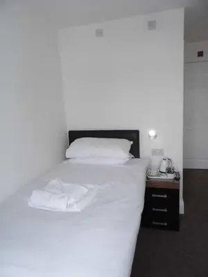 a bedroom with a white bed and a night stand at The Kerswell Hotel Sea Front in Morecambe