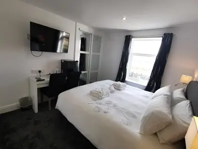 a bedroom with a white bed with a window and a desk at The Kerswell Hotel Sea Front in Morecambe