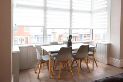 a dining room with a table and chairs and windows at Blackbird Luxury Apartments Room 3 in Blackpool