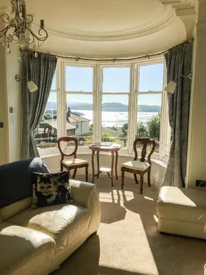 a living room with a couch and chairs and windows at East Bank Apartment in Grange Over Sands