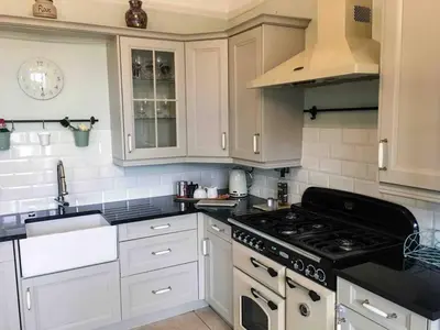 a kitchen with white cabinets and a stove top oven at East Bank Apartment in Grange Over Sands