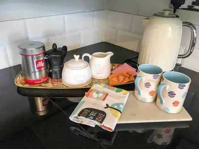 a counter top with cups and tea pots on it at East Bank Apartment in Grange Over Sands