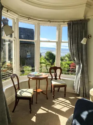 a room with a table and two chairs and a window at East Bank Apartment in Grange Over Sands