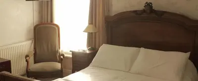 a bedroom with a bed and a chair and a window at Leofric Legends in Blackpool