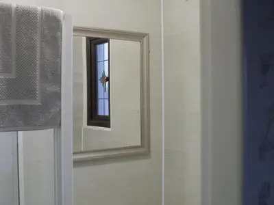 a mirror in a bathroom next to a window at Leofric Legends in Blackpool