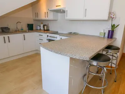 a kitchen with white cabinets and a counter with stools at Shorefields One in Morecambe