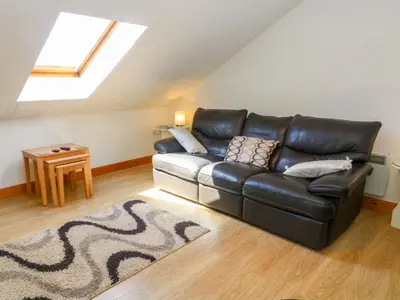 a black leather couch in a living room with a window at Shorefields Two in Morecambe