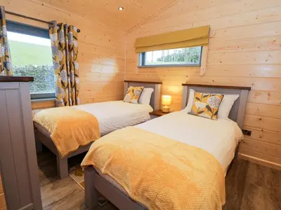 two beds in a room with wooden walls at Oak Lodge in Ulverston