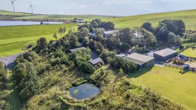 an aerial view of a farm with a building and a pond at Oak Lodge in Ulverston