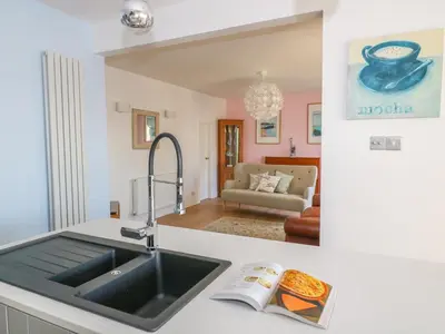 a kitchen with a sink and a living room at Shady Bowers in Carnforth
