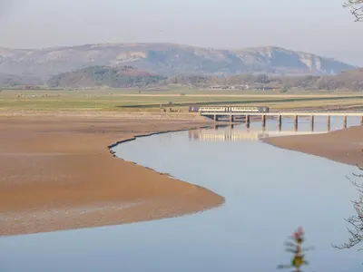 a bridge over a body of water with mountains in the background at Shady Bowers in Carnforth