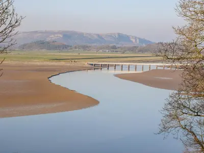 a bridge over a body of water with mountains in the background at Shady Bowers in Carnforth