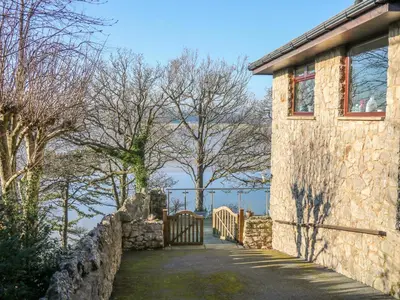 a stone house with a gate and a stone wall at Shady Bowers in Carnforth