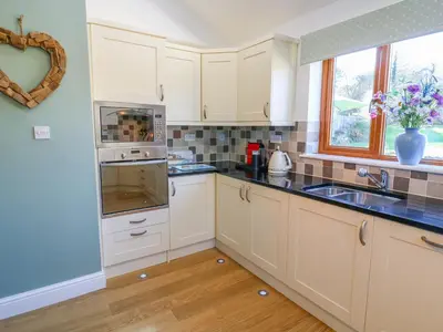 a kitchen with white cabinets and a sink at Langtree in Carnforth
