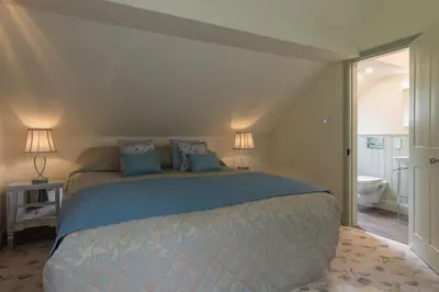 a bedroom with a large bed and a bathroom at Woodhaven - Luxury 4 bedroom rural retreat with hot tub near to Lake District in Grange Over Sands