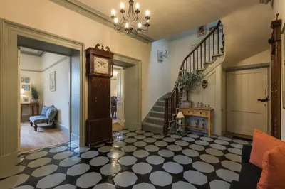 a living room with a clock and a staircase at Woodhaven - Luxury 4 bedroom rural retreat with hot tub near to Lake District in Grange Over Sands