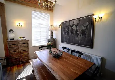a dining room with a wooden table and a painting on the wall at Pippin Lodge Lytham in Lytham St Annes