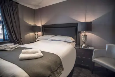 a bedroom with a large bed and a chair at N'ista Boutique Rooms Birkdale, Southport in Southport