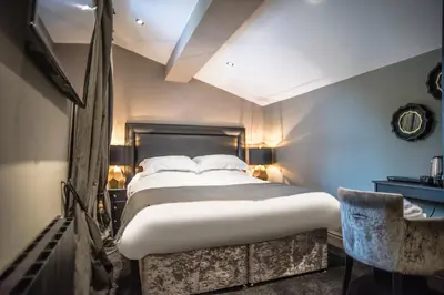 a bedroom with a large bed and a chair at N'ista Boutique Rooms Birkdale, Southport in Southport
