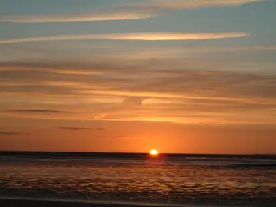 a sunset on the beach with the sun in the horizon at The Kathrene in Fleetwood